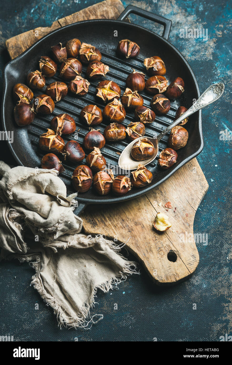Roasted chestnuts in cast iron pan over dark blue background Stock