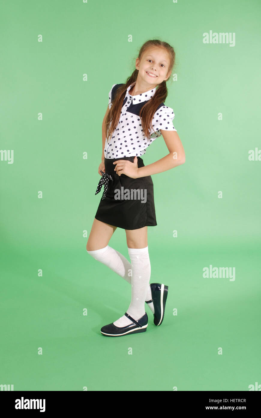 Beautiful young girl in school uniform isolated on green Stock Photo