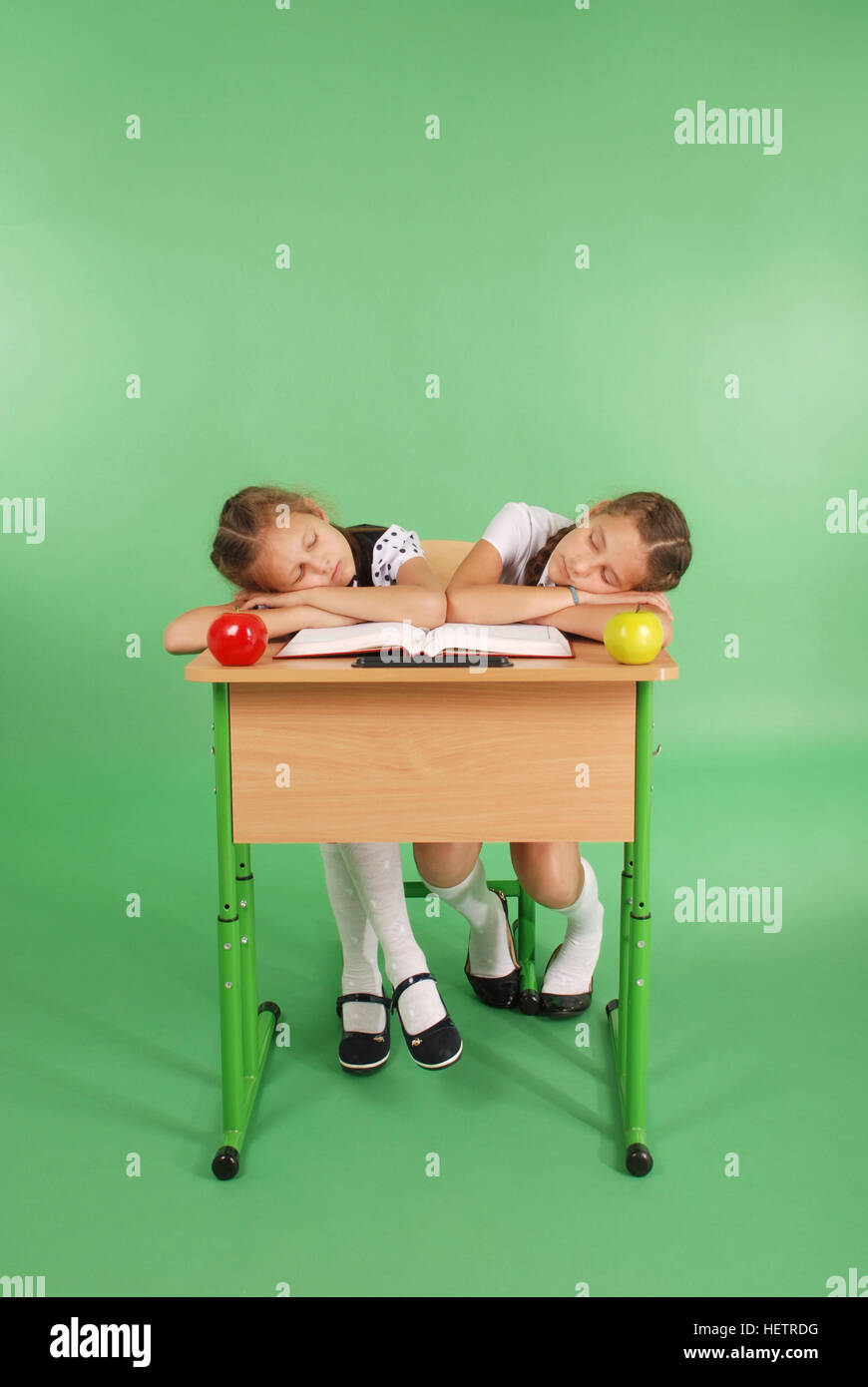 Two school girls sleeping on a stack of books at her desk isolated on ...