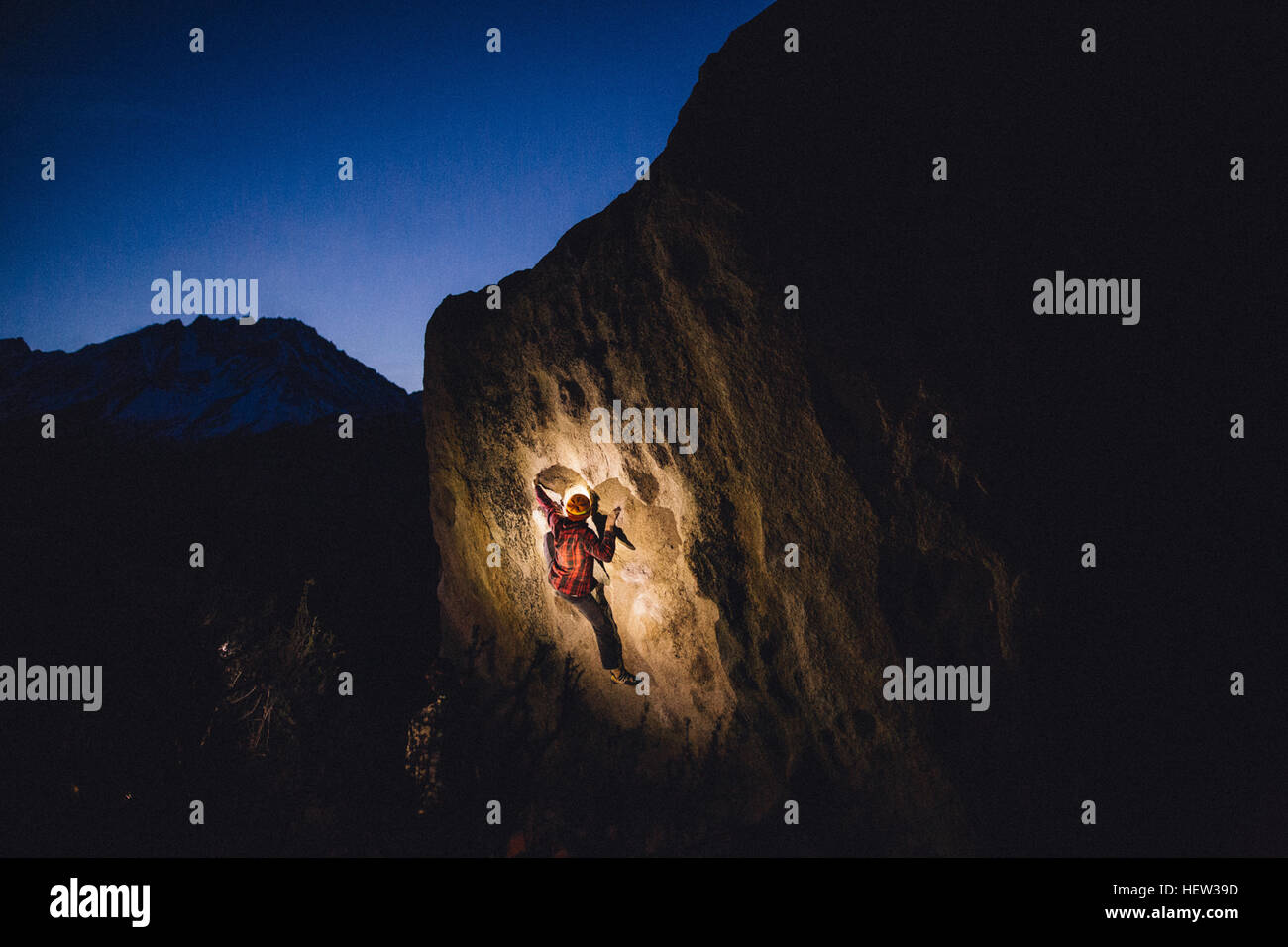 Young man rock climbing at night, Buttermilk Boulders,