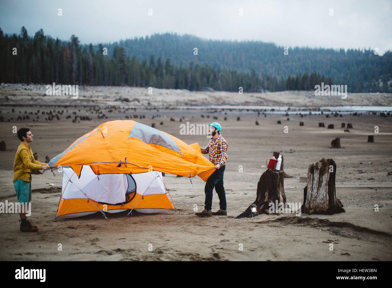 Two young men setting up tent on beach, Huntington Lake, California, USA Stock Photo