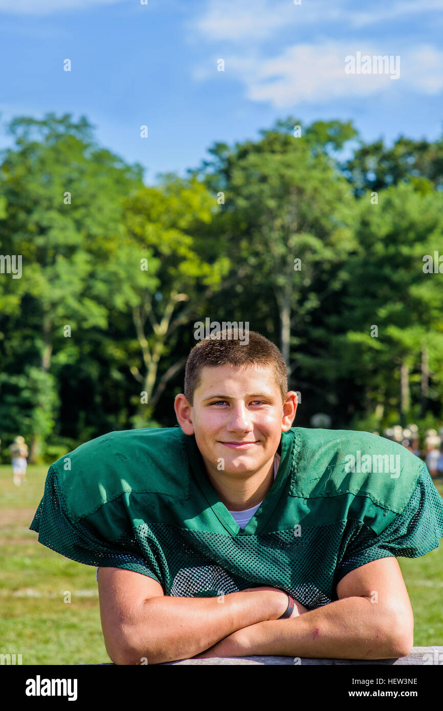 Portrait teenage male American football player with arms folded at