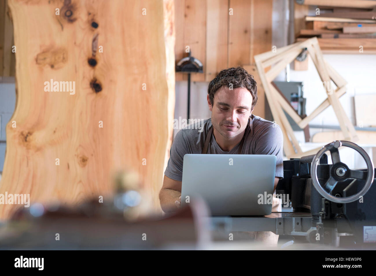 Carpenter at his workshop, using laptop Stock Photo
