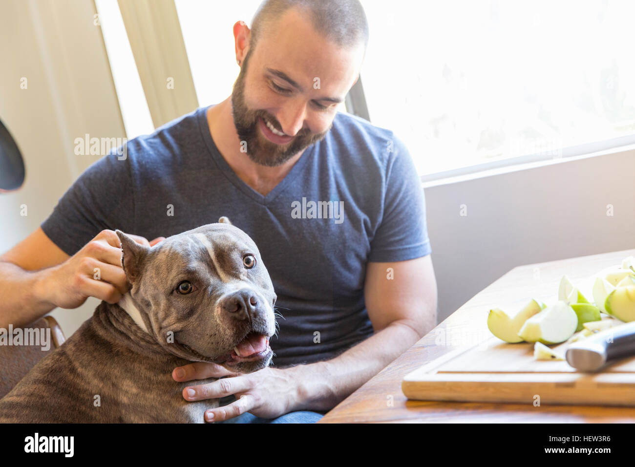 Portrait of mid adult man petting dog in kitchen Stock Photo