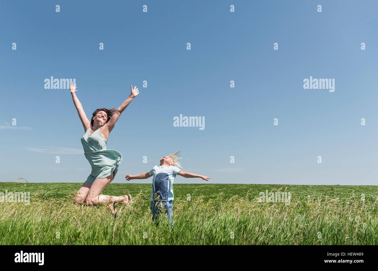 Mother and son jumping for joy in field Stock Photo
