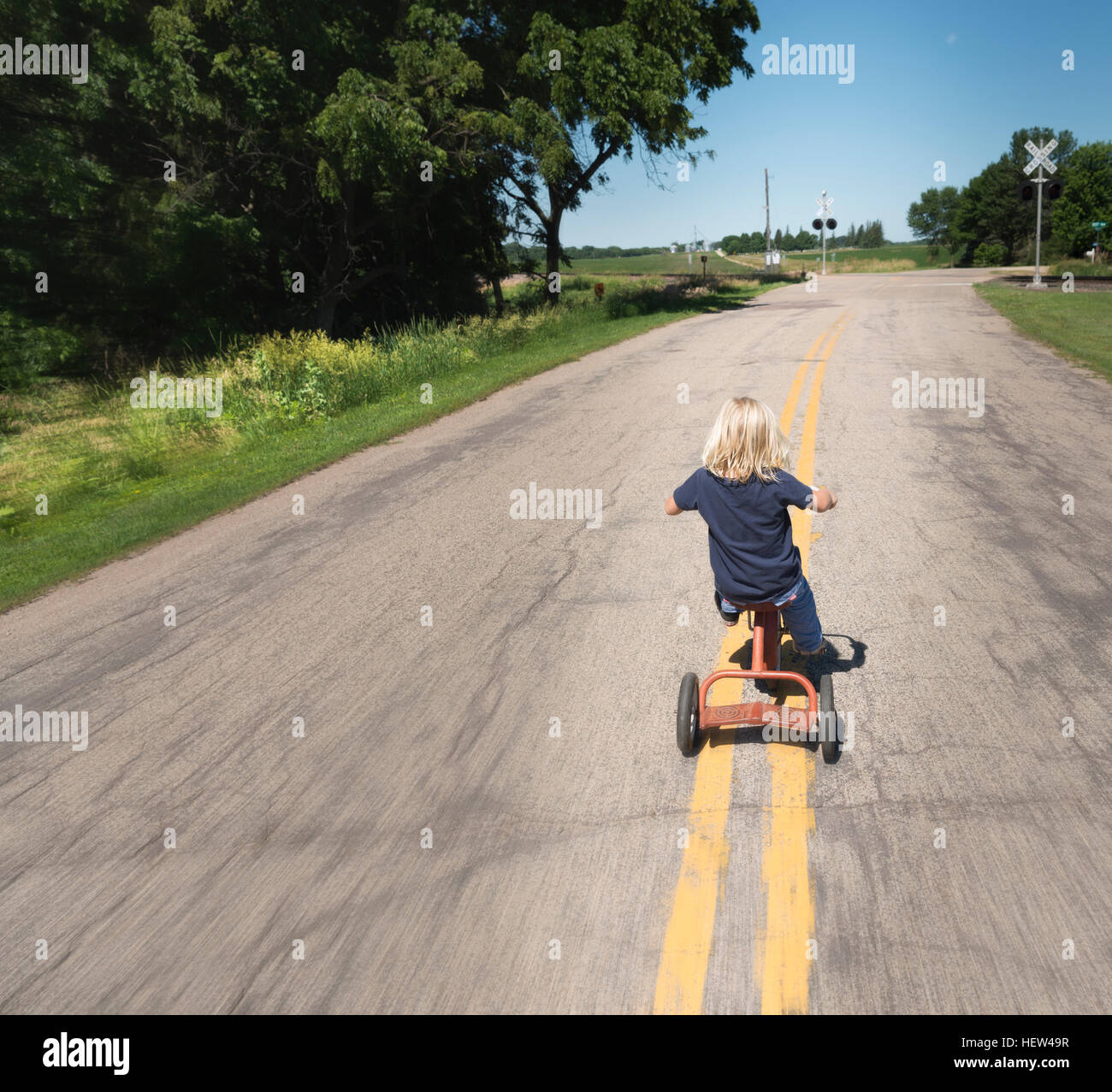 Rear view of boy riding bicycle on road Stock Photo - Alamy