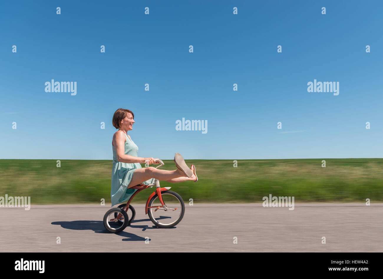 Side view of woman riding tricycle in rural area Stock Photo