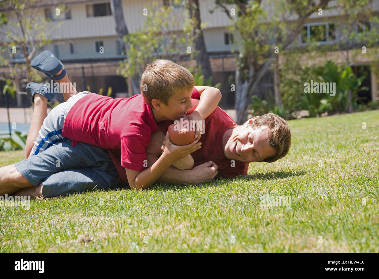 Boy tackling father playing american football in park Stock Photo