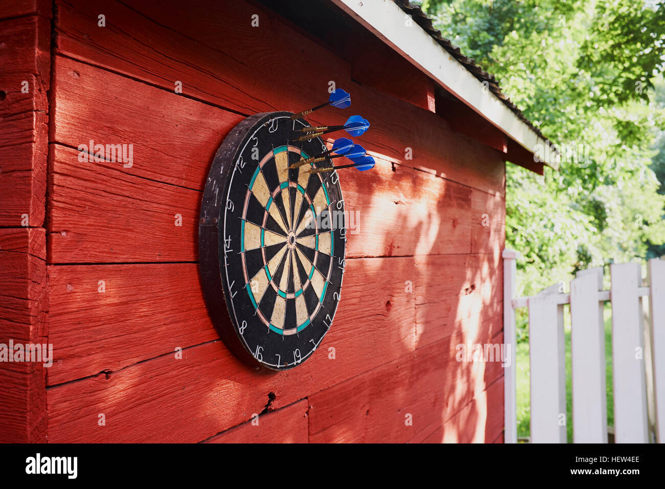 Dartboard hanging on shed, darts in board Stock Photo