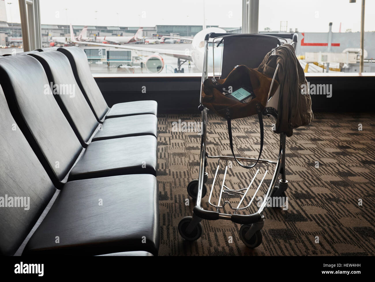 Smartphone in shoulder bag in luggage trolley in airport lounge Stock Photo