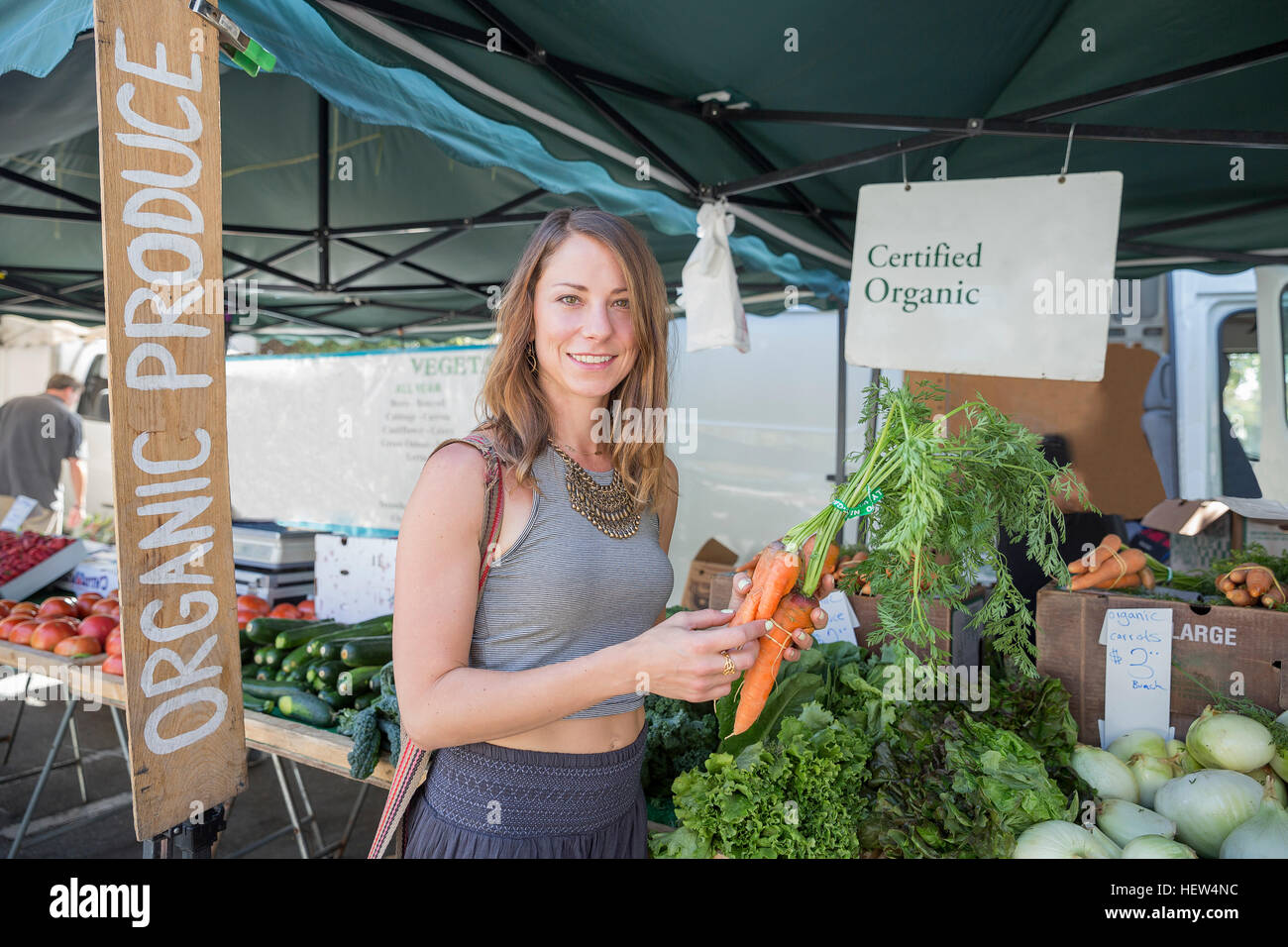 Woman at fruit and vegetable stall holding carrots Stock Photo