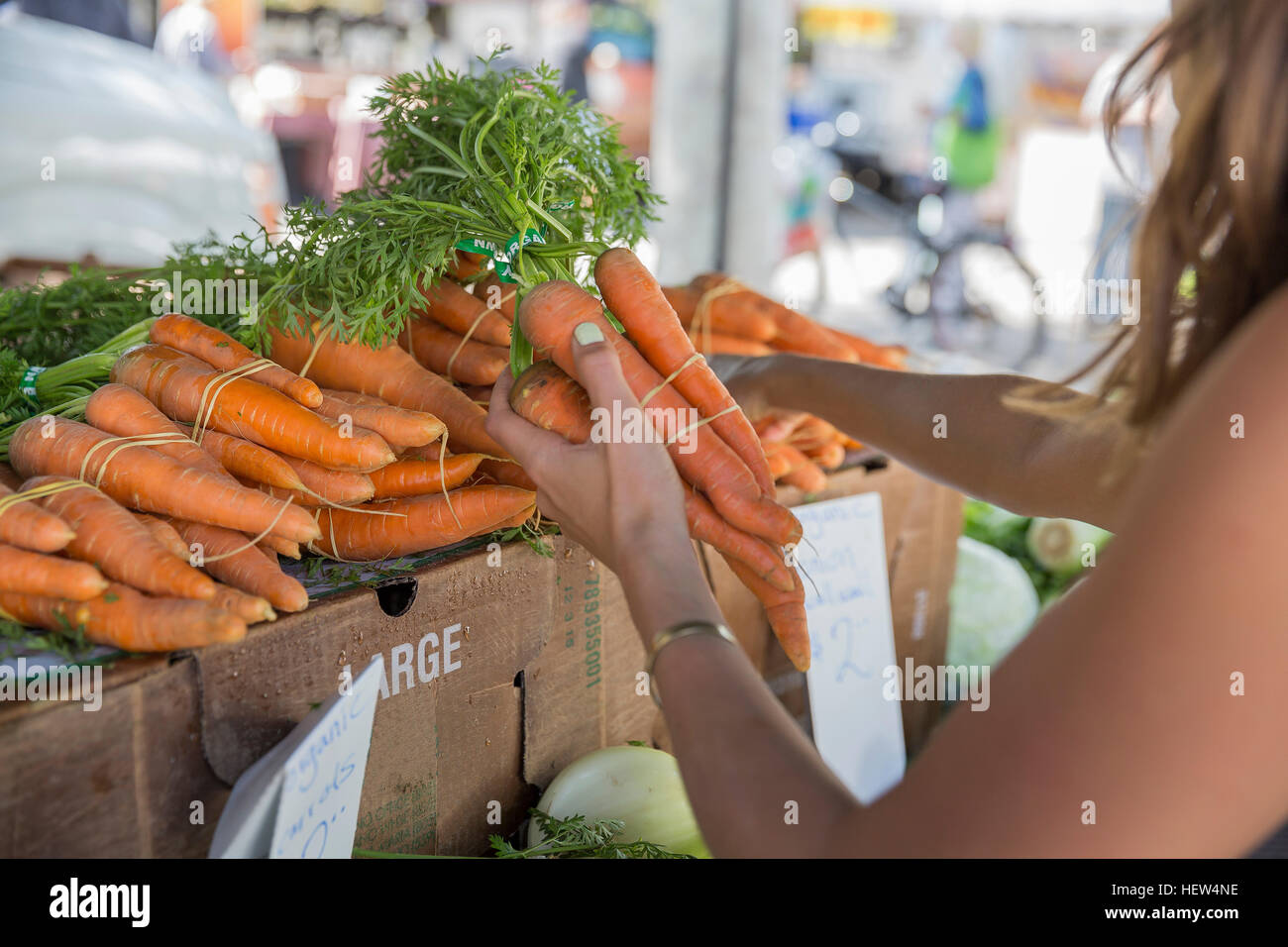 Woman at fruit and vegetable stall selecting carrots Stock Photo