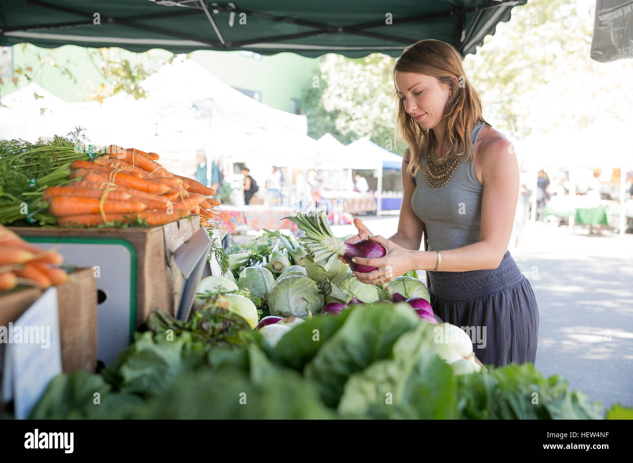 Woman at fruit and vegetable stall selecting red onions Stock Photo
