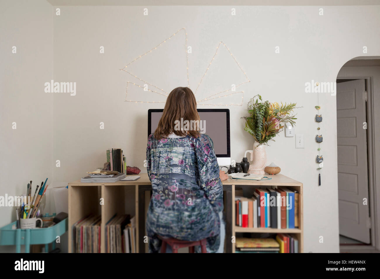 Rear view of woman sitting at desk Stock Photo - Alamy