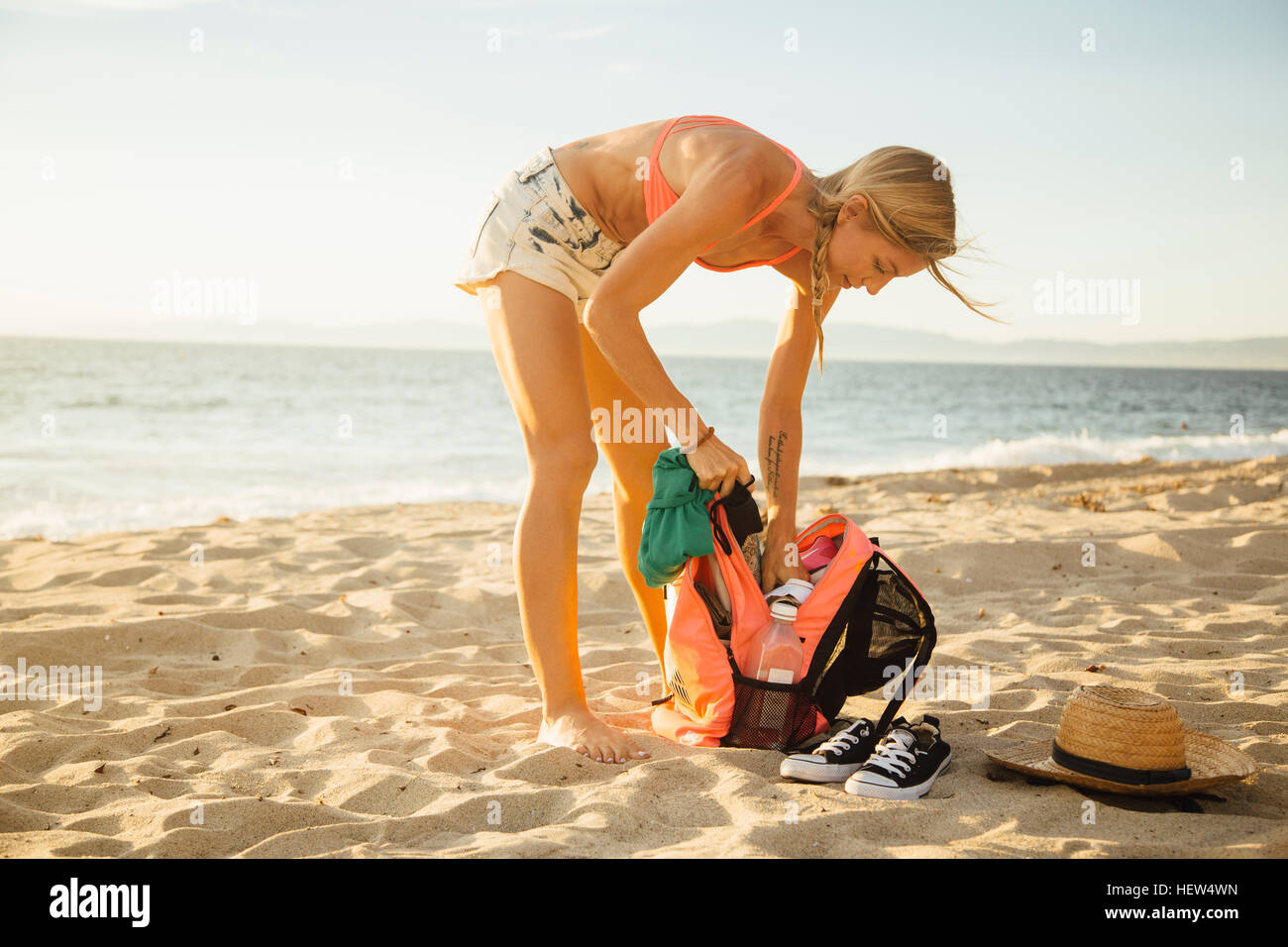 Woman on beach searching in back pack Stock Photo