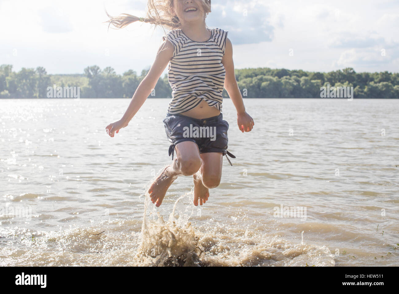 Girl jumping and splashing in river Stock Photo