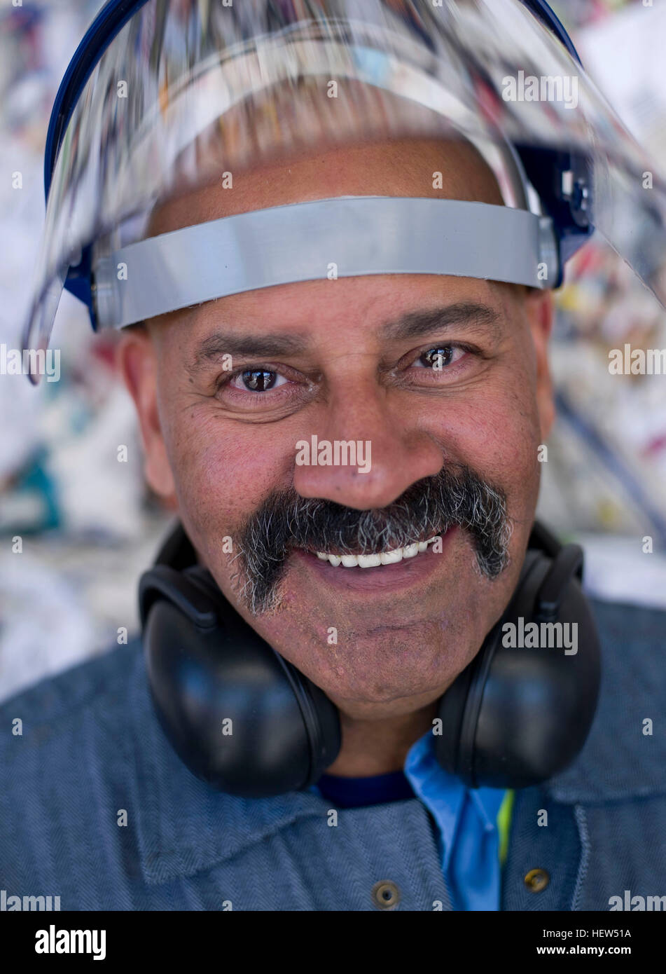 Portrait of male worker in hard hat visor, in front of rubbish at recycling plant Stock Photo