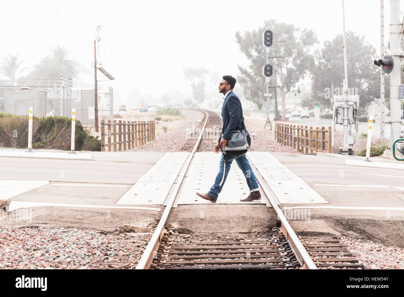 Young man walking across level crossing, side view Stock Photo