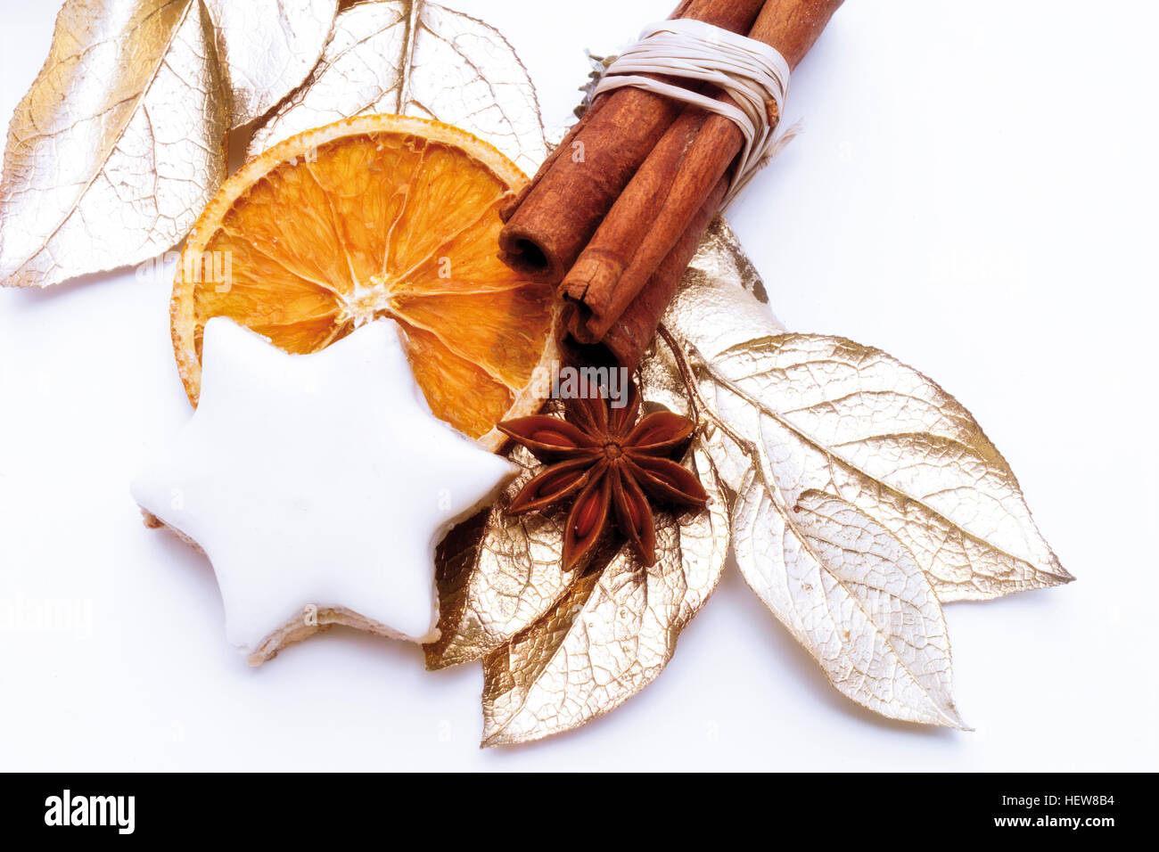 Star anise, bound cinnamon sticks, a biscuit, and gold painted dried bay leaves, Christmas