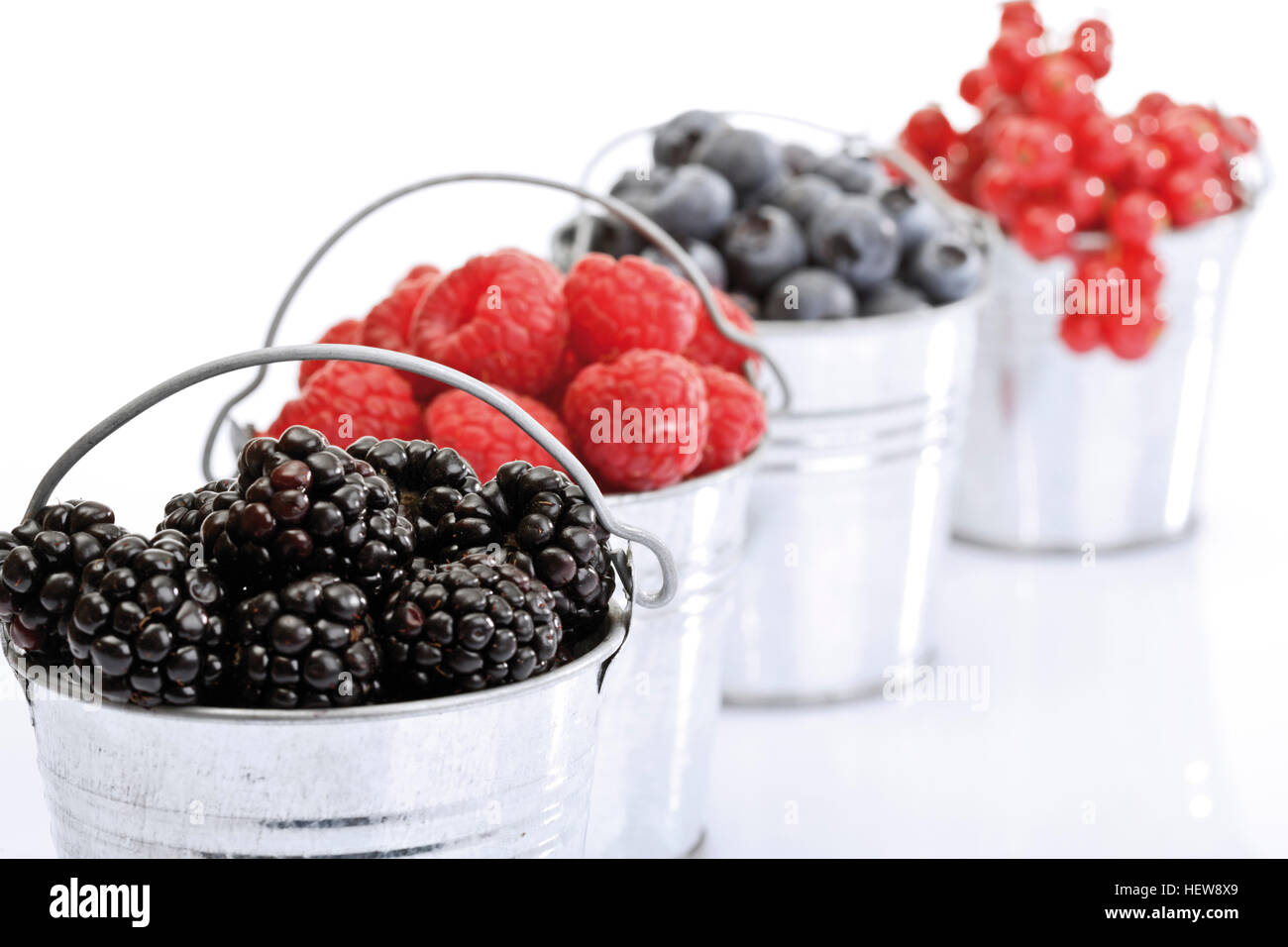 Four small galvanized buckets containing red currants, raspberries, blueberries and blackberries Stock Photo