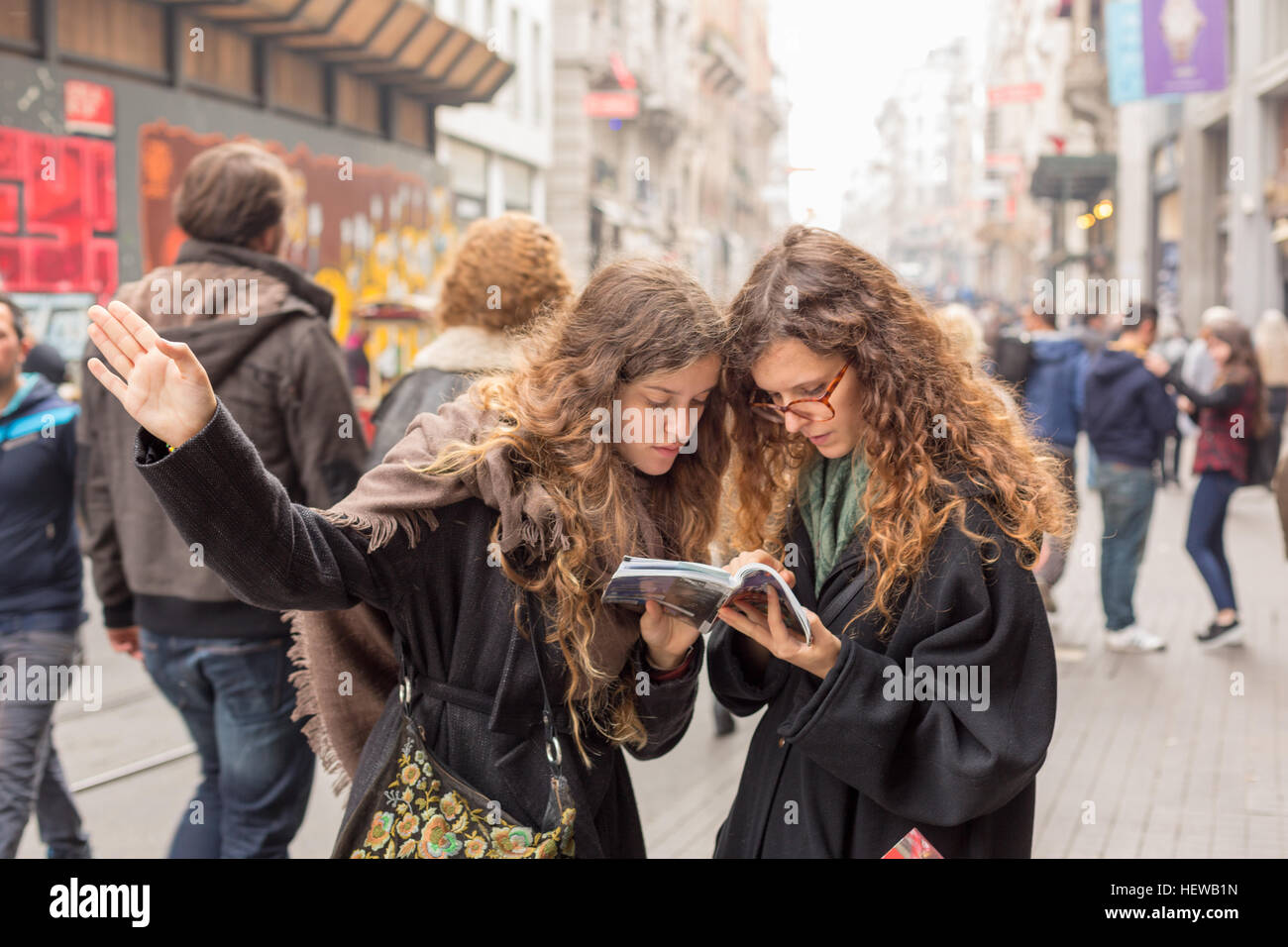 young women tourists look for a place from travel guide book in istiklal street,Istanbul Stock Photo