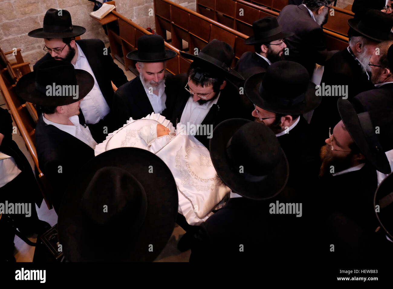 An Ultra Orthodox Jewish father holds newly circumcised baby son during Circumcision - Brit Mila Ceremony inside the reconstructed Hurva synagogue at the Jewish Quarter Old city East Jerusalem Israel Stock Photo