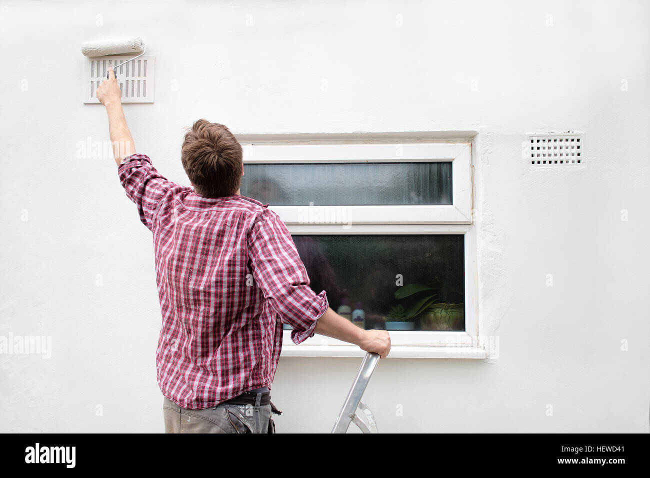 A man paints an exterior wall of his home Stock Photo Alamy