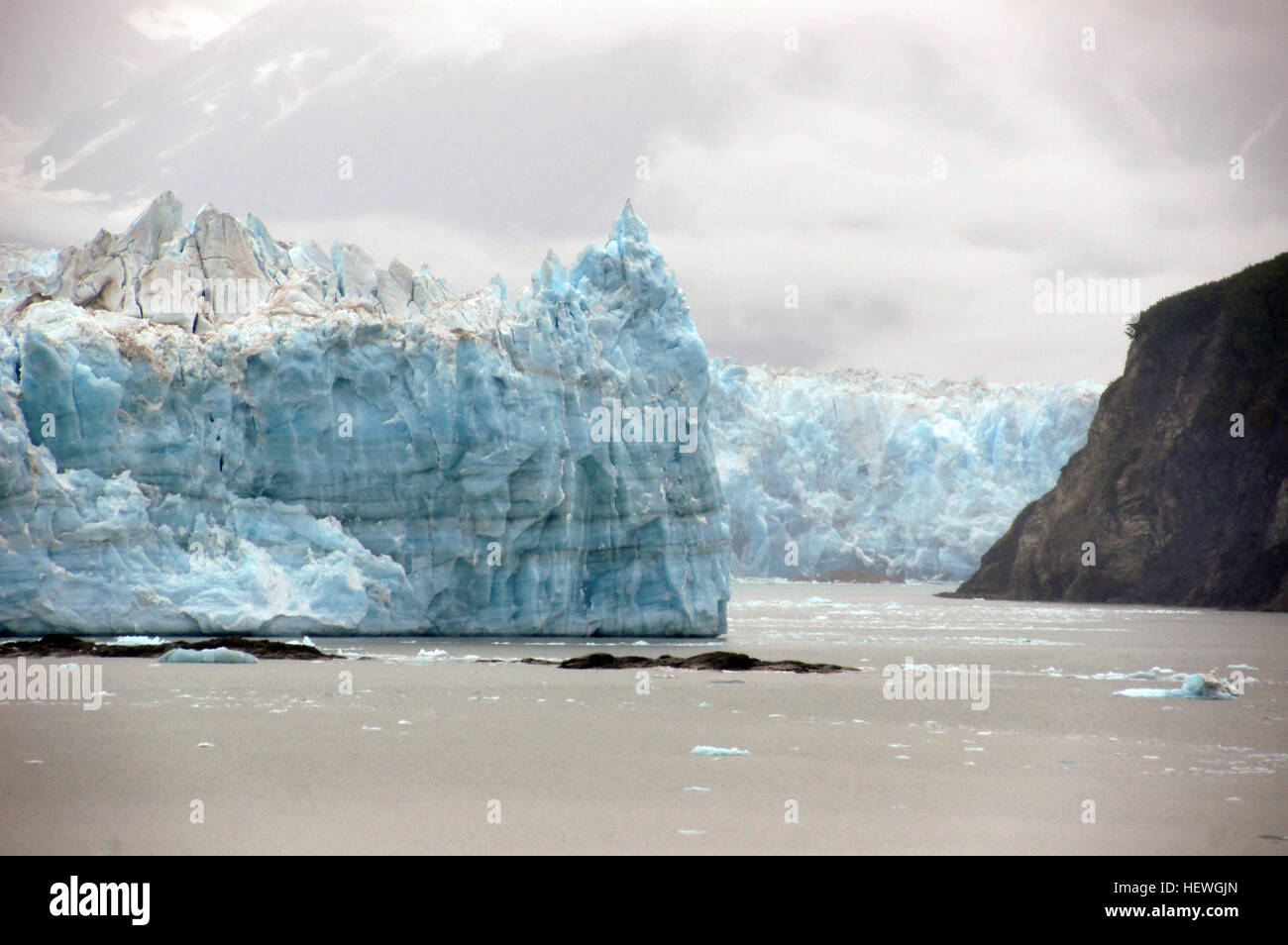 Hubbard Glacier is defying the global paradigm of valley or mountain glacier shrinkage and retreat in response to global climate warming. Hubbard Glacier is the largest of eight calving glaciers in Alaska that are currently increasing in total mass and advancing. All of these glaciers calve into the sea, are at the heads of long fiords, have undergone retreats during the last 1,000 years, calve over relatively shallow submarine moraines, and have unusually small ablation areas compared to their accumulation areas. Stock Photo