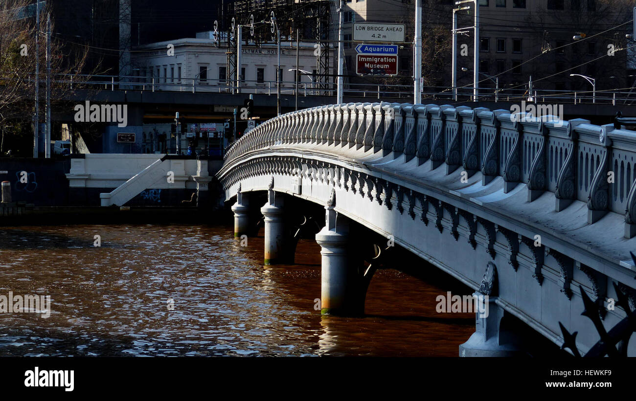 Queens Bridge which crosses the Yarra at the southern extension of Market Street, replaced an earlier timber footbridge erected in 1860, known as Falls Bridge. The present structure, named after Queen Victoria, was designed by Frederick M Hynes, the Chief Design Engineer for the &quot;Harbour Jetties and Coast Works Department&quot; of the Public Works Department. The chief contractor for its construction was David Munro, who also erected Princes Bridge, and the Sandridge Railway Bridge over the Yarra River. The bridge was officially opened by the Governor, Lord Hopetoun, on 18 April 1890. Que Stock Photo