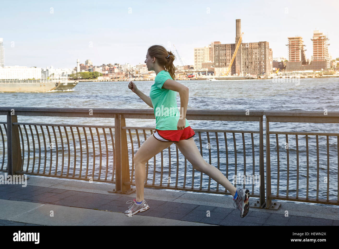 Young woman exercising outdoors, running beside river, New York City, USA Stock Photo