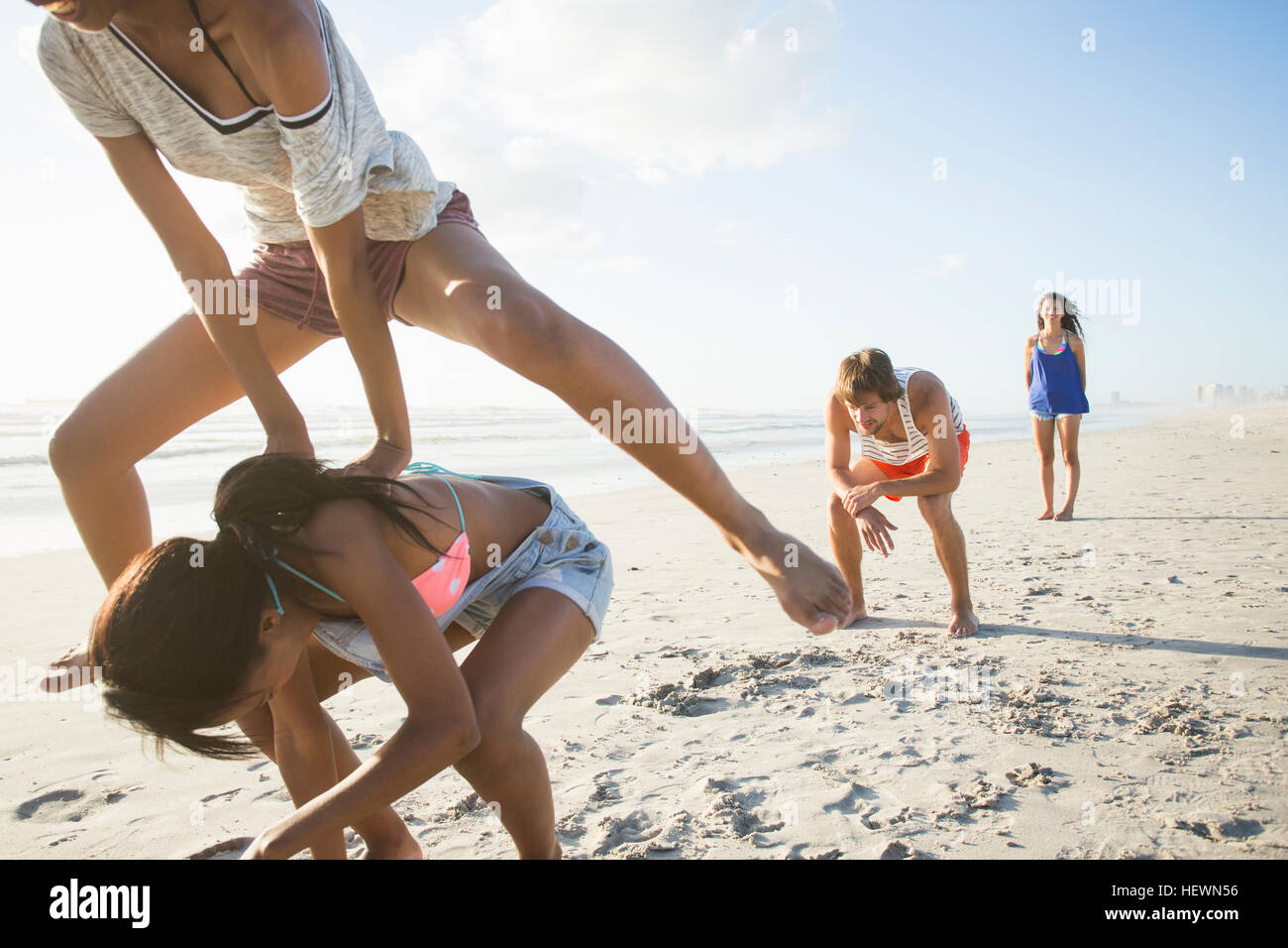 Young man and three female friends playing leapfrog on beach, Cape Town, South Africa Stock Photo