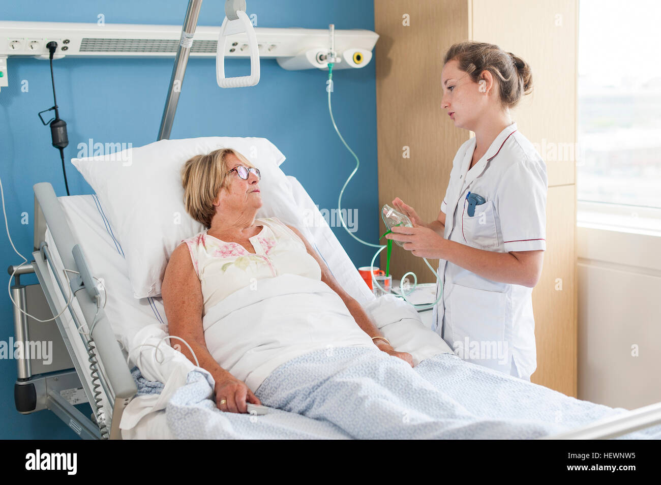 Nurse tending to patient in hospital bed Stock Photo