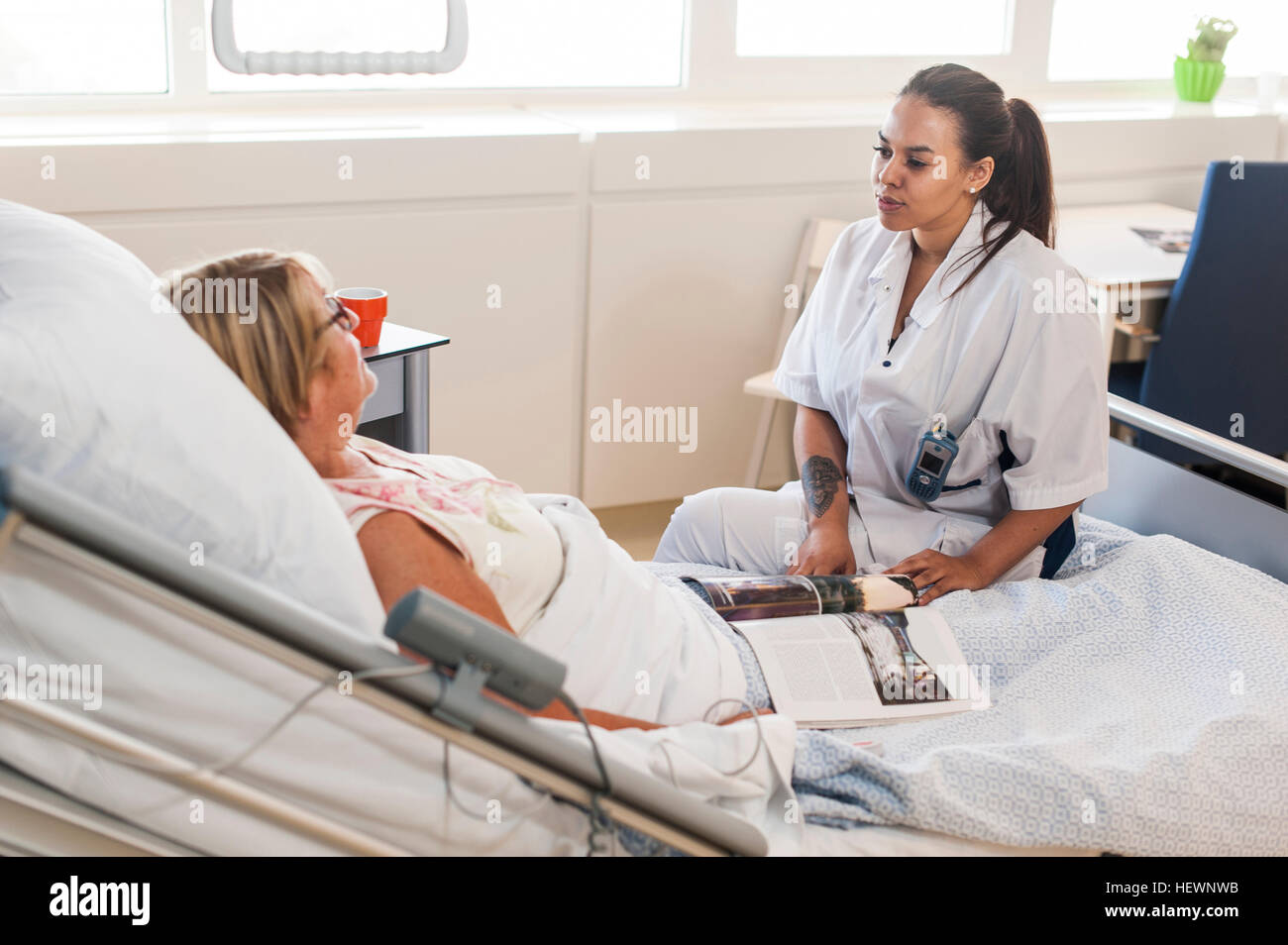 Nurse tending to patient in hospital bed Stock Photo