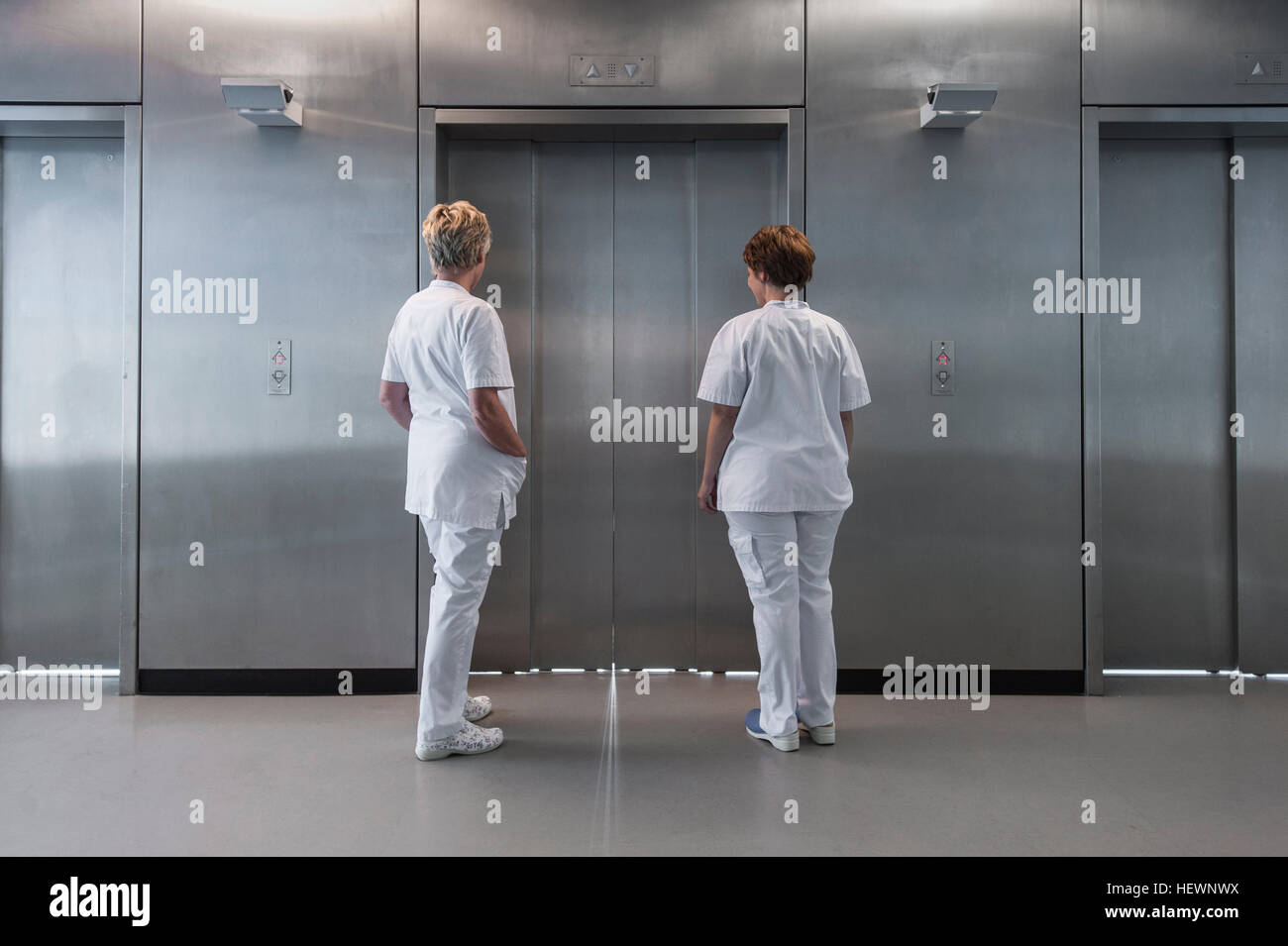 Rear view of nurses in hospital waiting for elevator Stock Photo