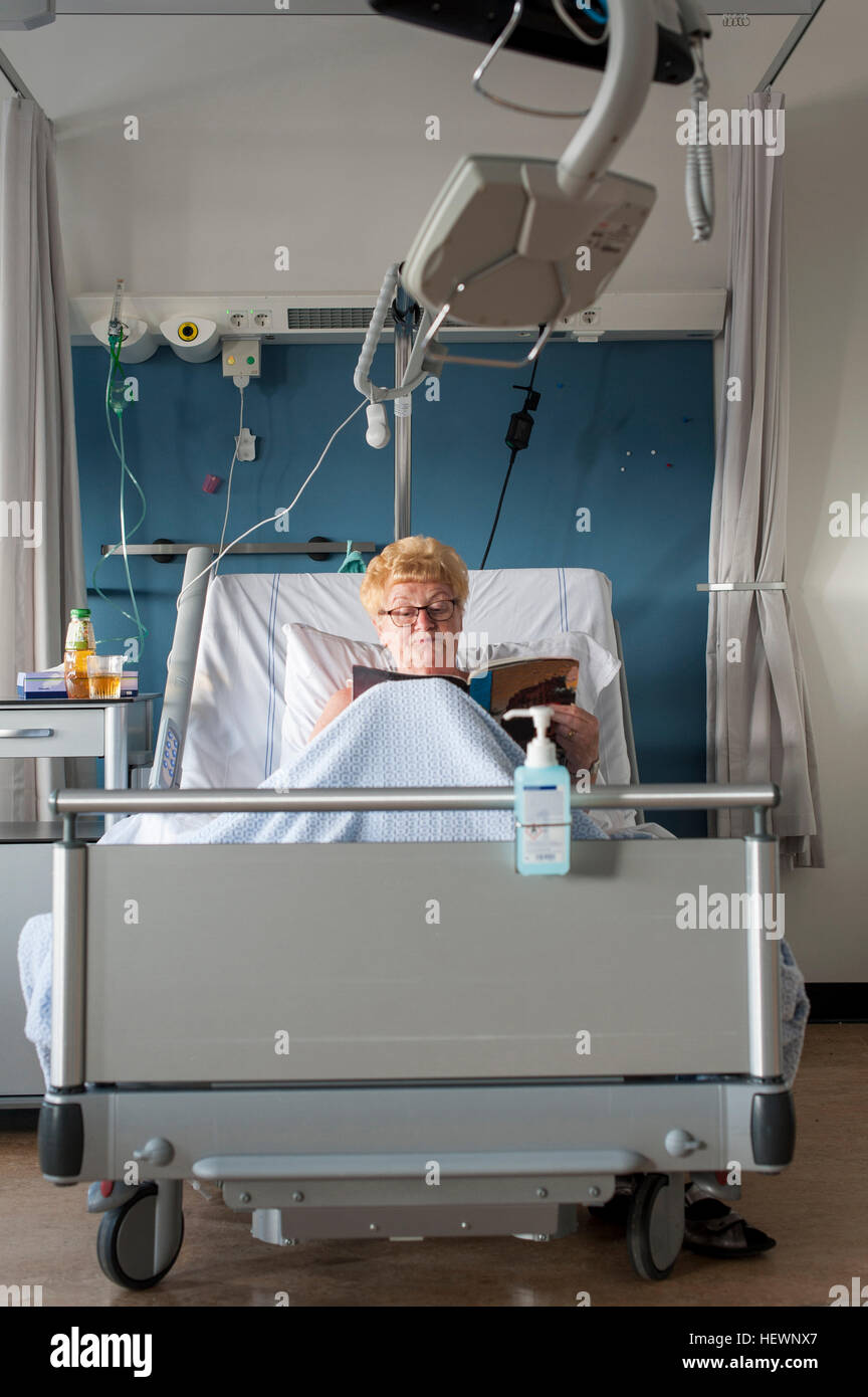 Patient in hospital bed reading magazine Stock Photo