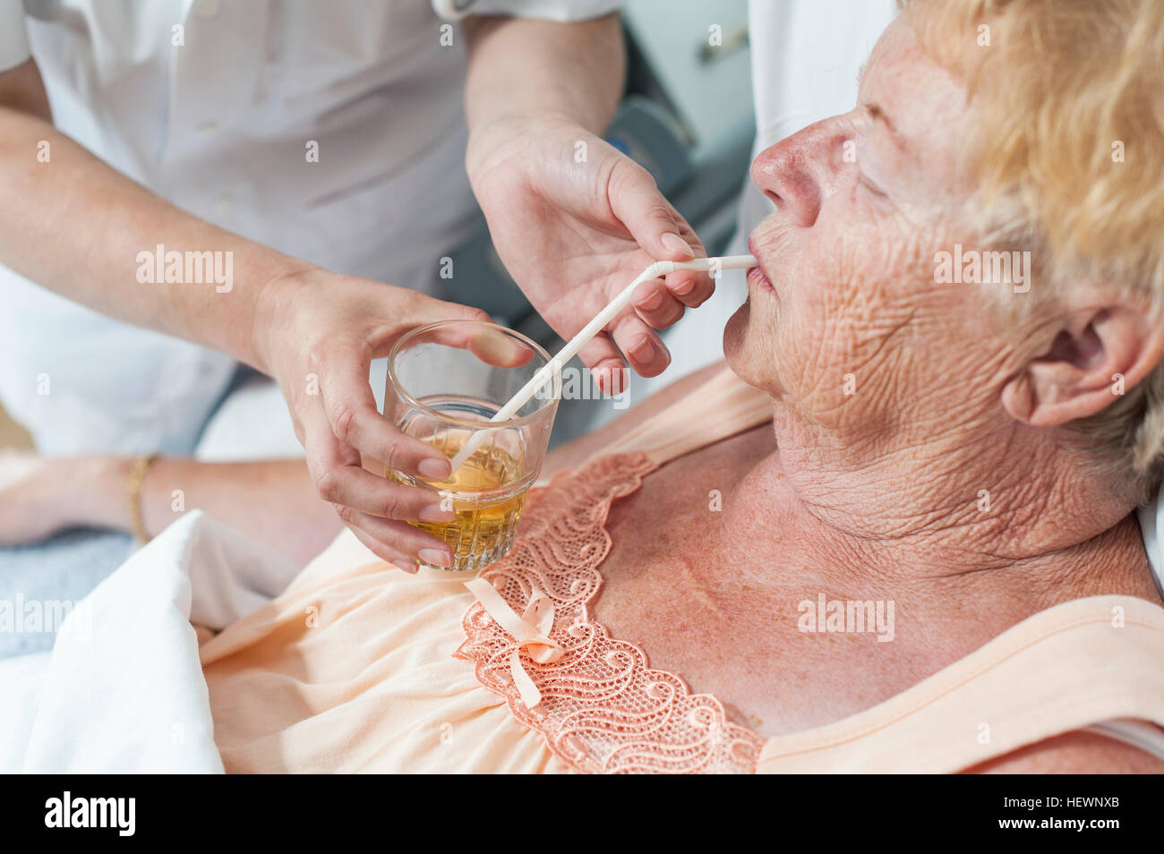 Nurse helping patient in hospital bed take a drink Stock Photo