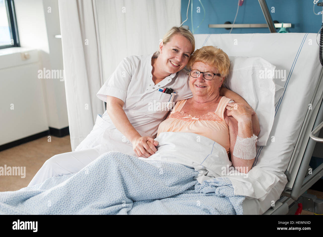 Nurse and patient on hospital bed looking at camera smiling Stock Photo