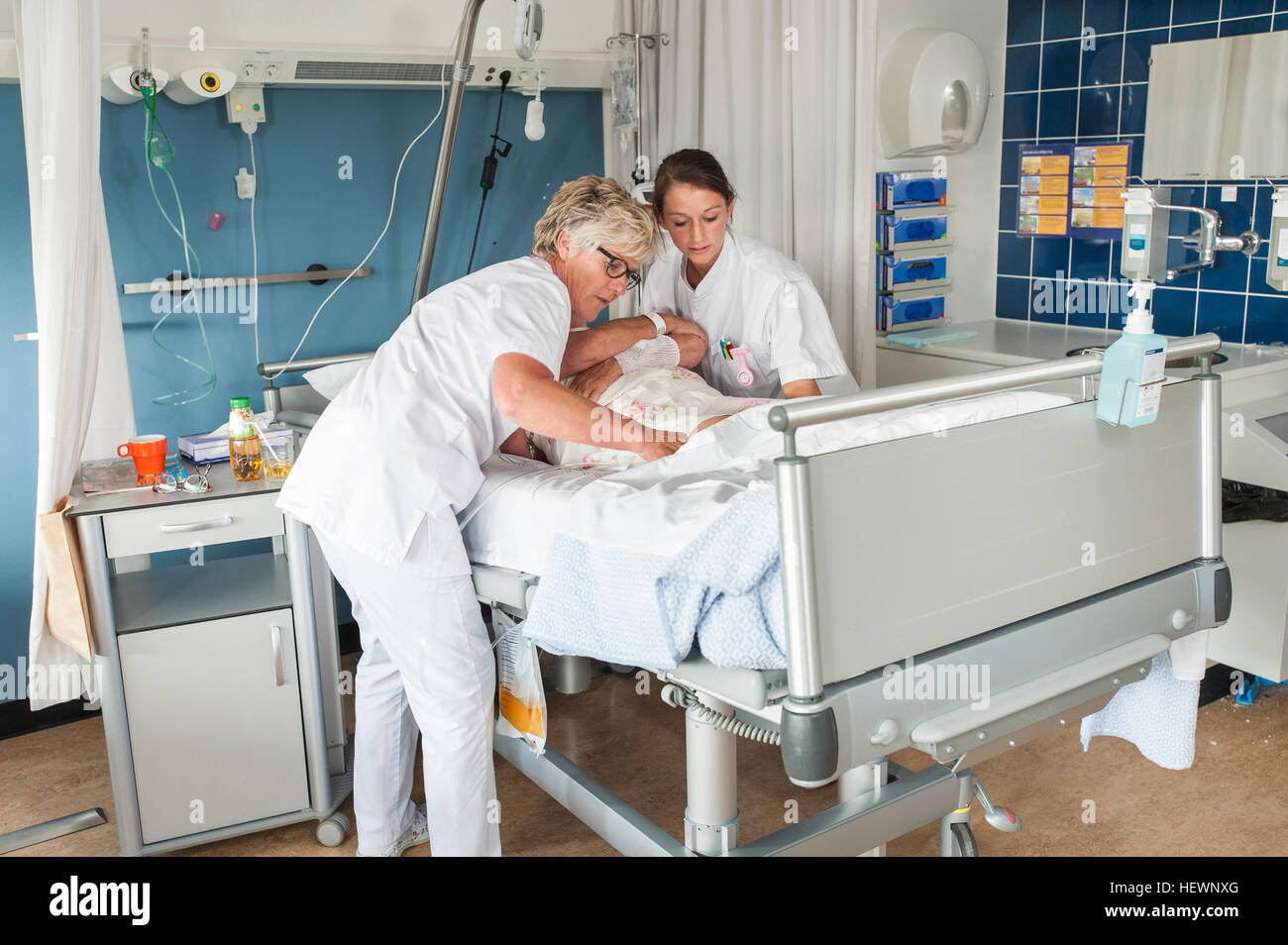 Nurses tending to patient in hospital bed Stock Photo