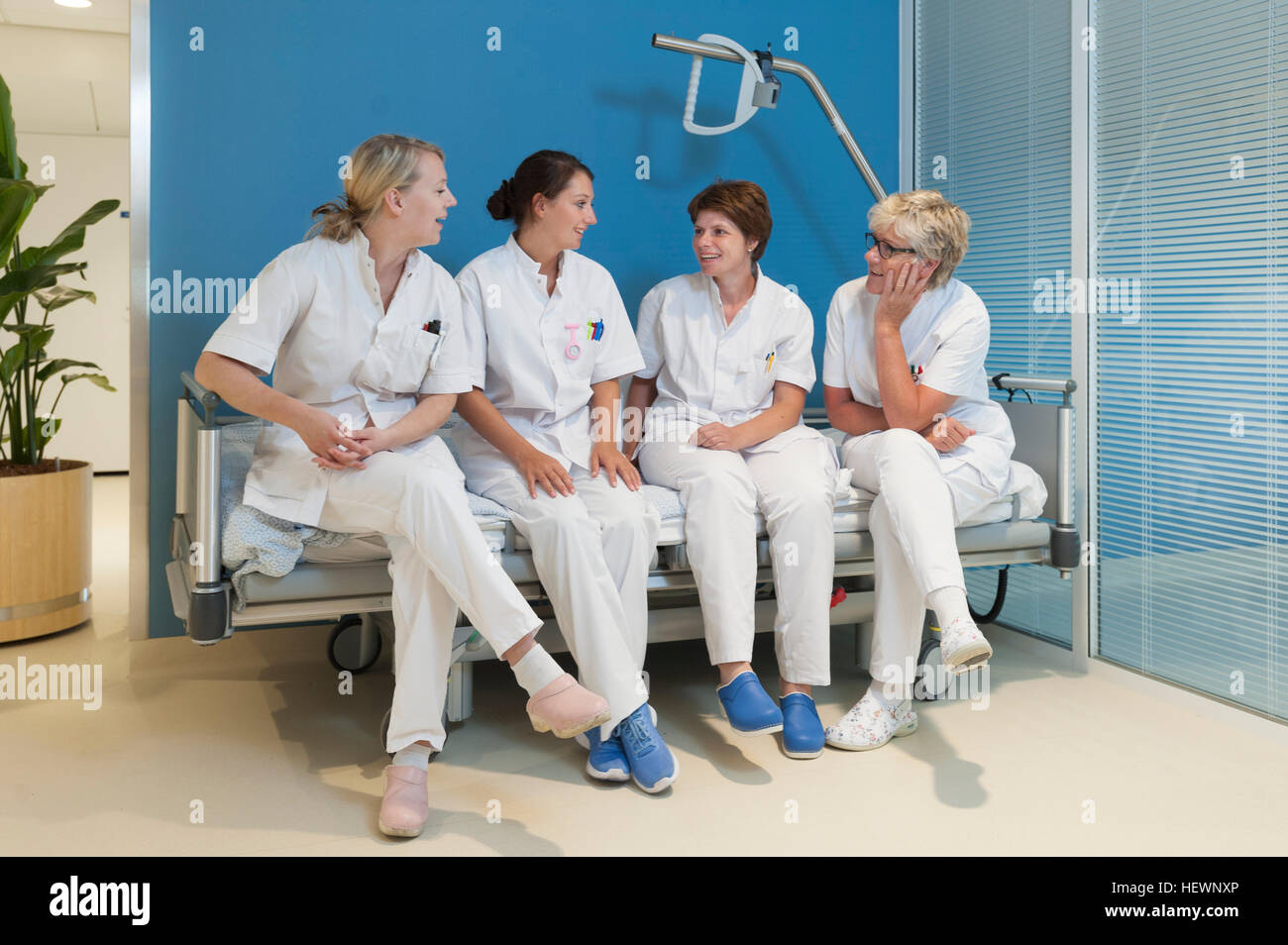 Nurses sitting side by side on bench in hospital, chatting Stock Photo