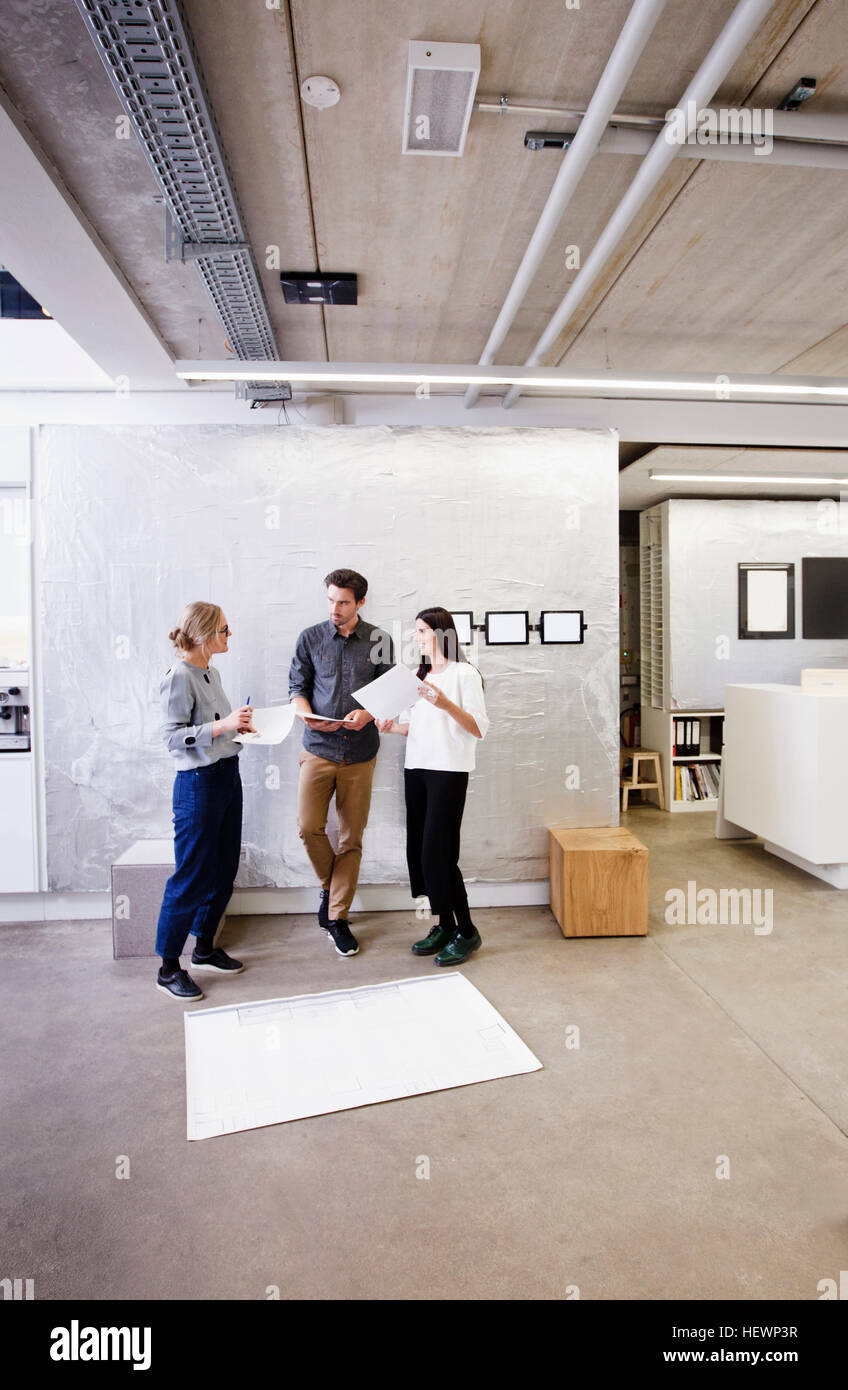 Architects in office discussing blueprints Stock Photo