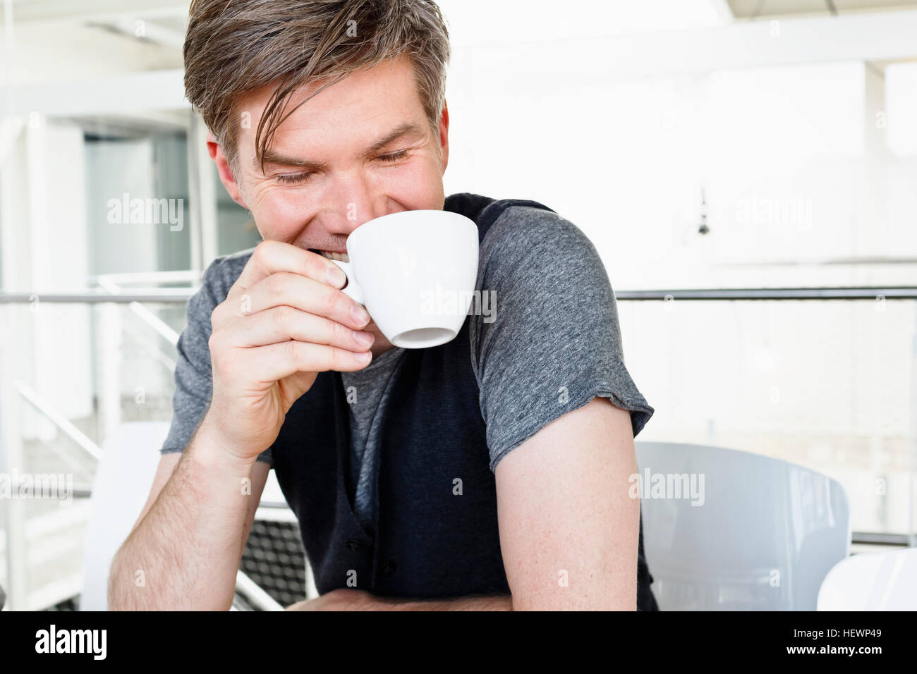 Man holding tea cup looking down smiling Stock Photo