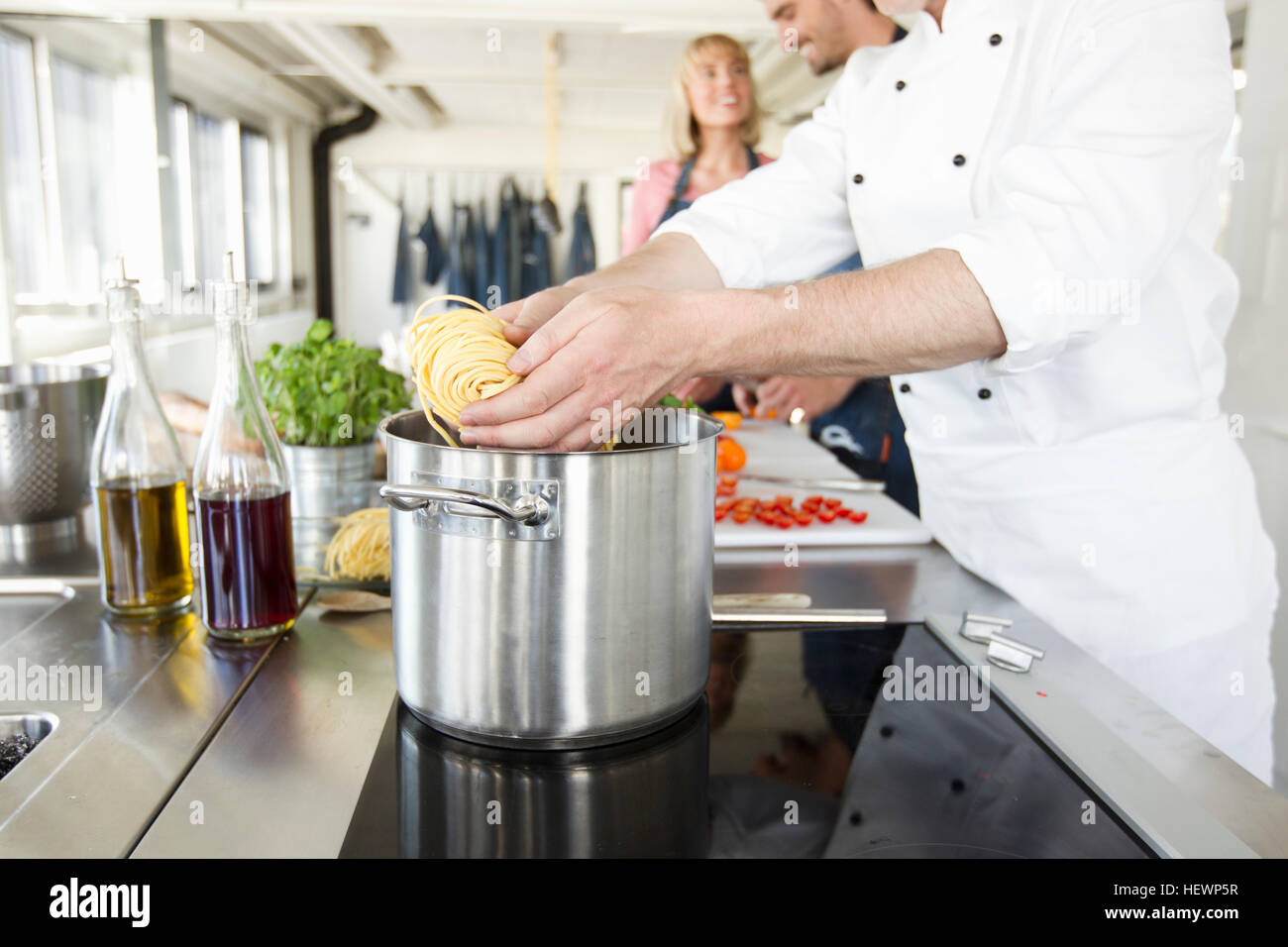 Chef adding pasta to saucepan Stock Photo
