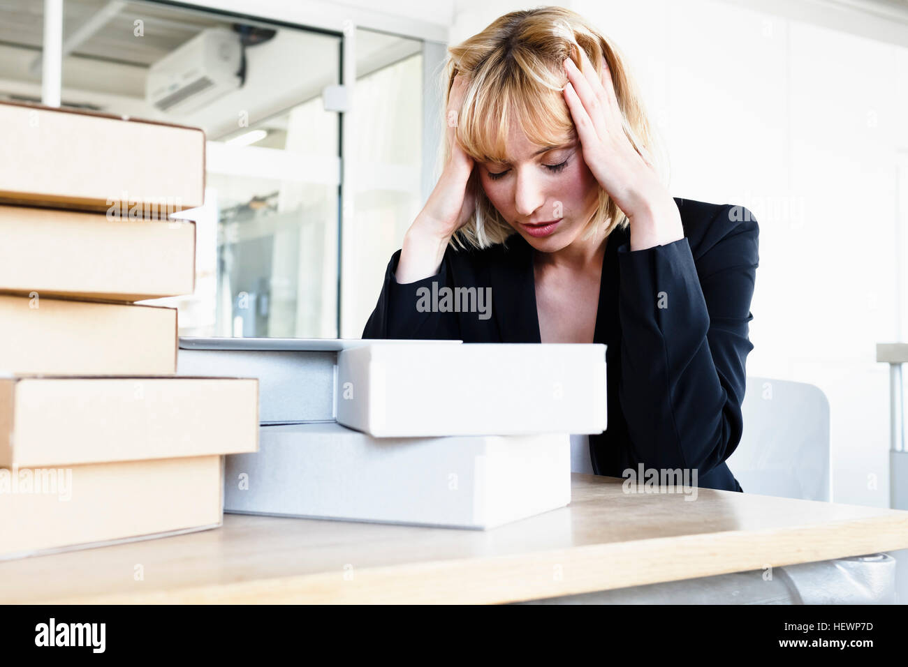 Business woman with stack of books, head in hands looking stressed Stock Photo