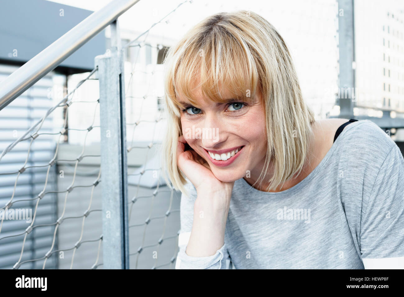 Portrait of blonde haired woman, hand on chin looking at camera smiling Stock Photo