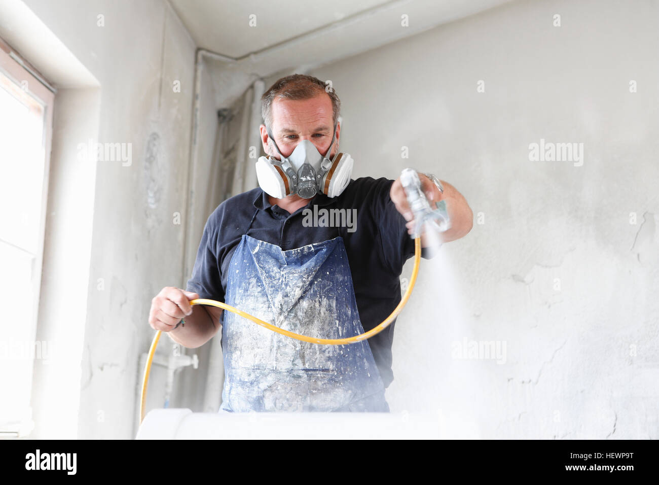 Man wearing protective mask spray painting timber Stock Photo