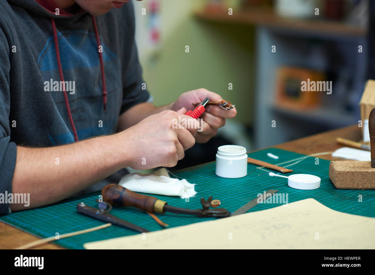 Male worker in leather making leather watch strap, mid