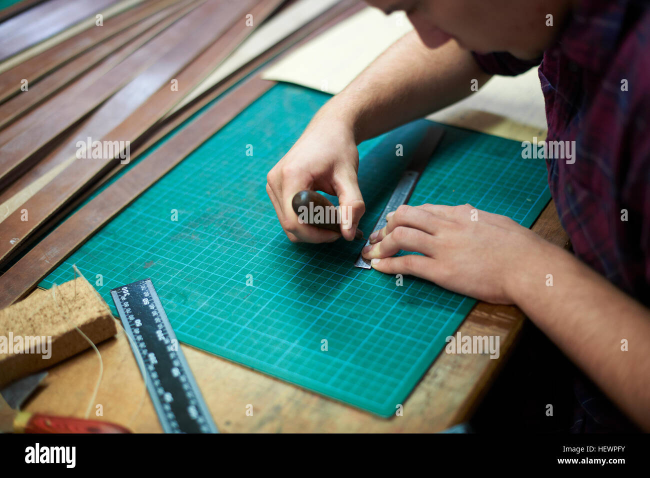 Male worker in leather measuring leather, using bradle Stock