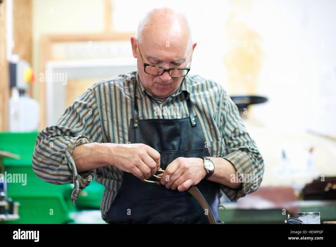 Male worker in leather polishing belt buckle Stock Photo Alamy