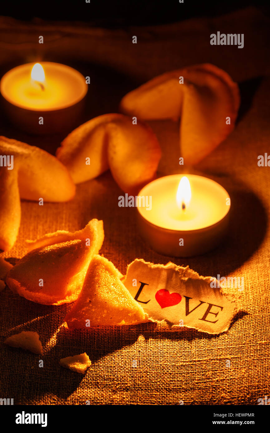 Cookies shaped like a tortellini with the word love written on a paper and two candles lit.Vertical image. Stock Photo