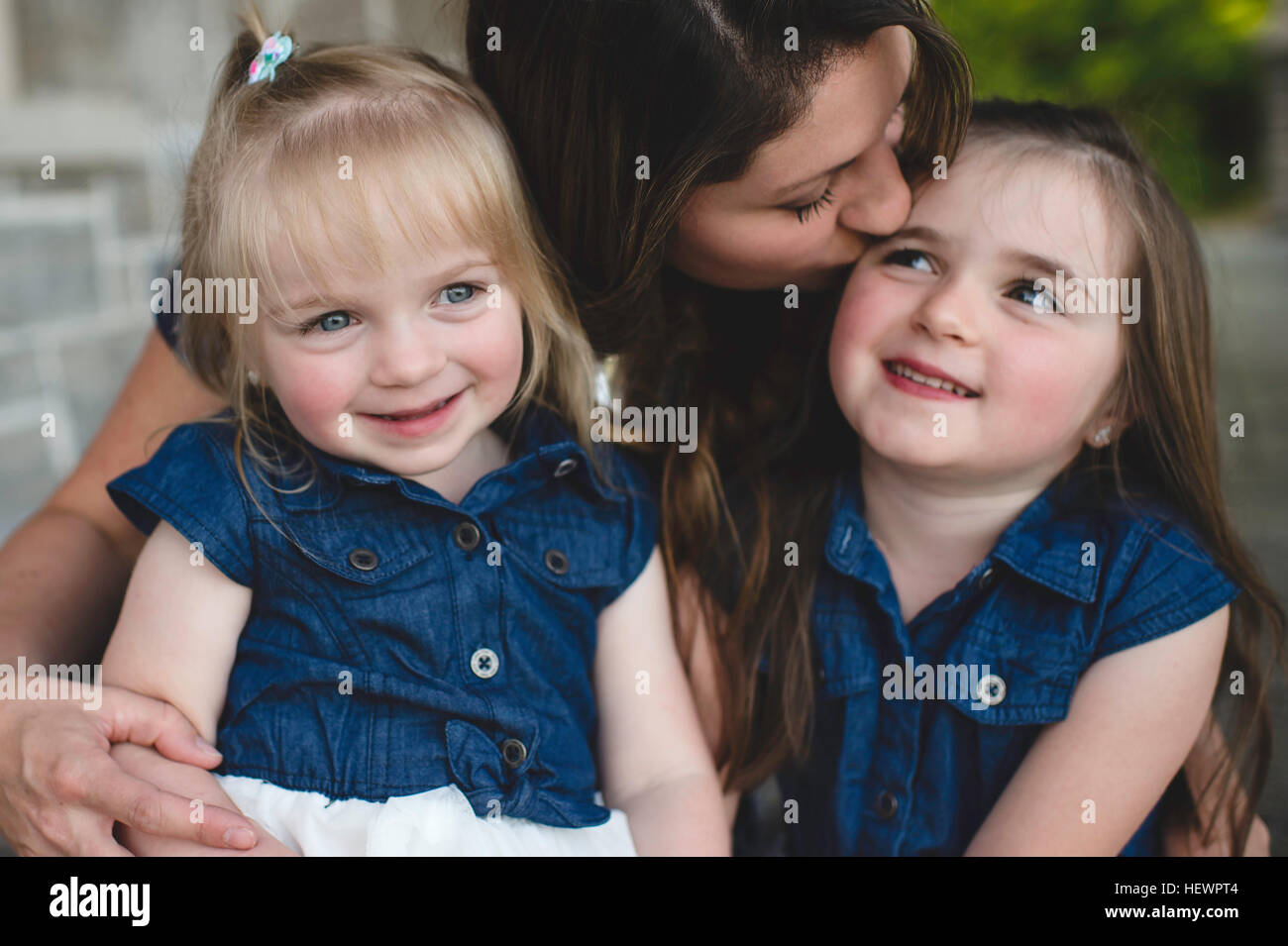 Girls sitting on mothers lap smiling Stock Photo